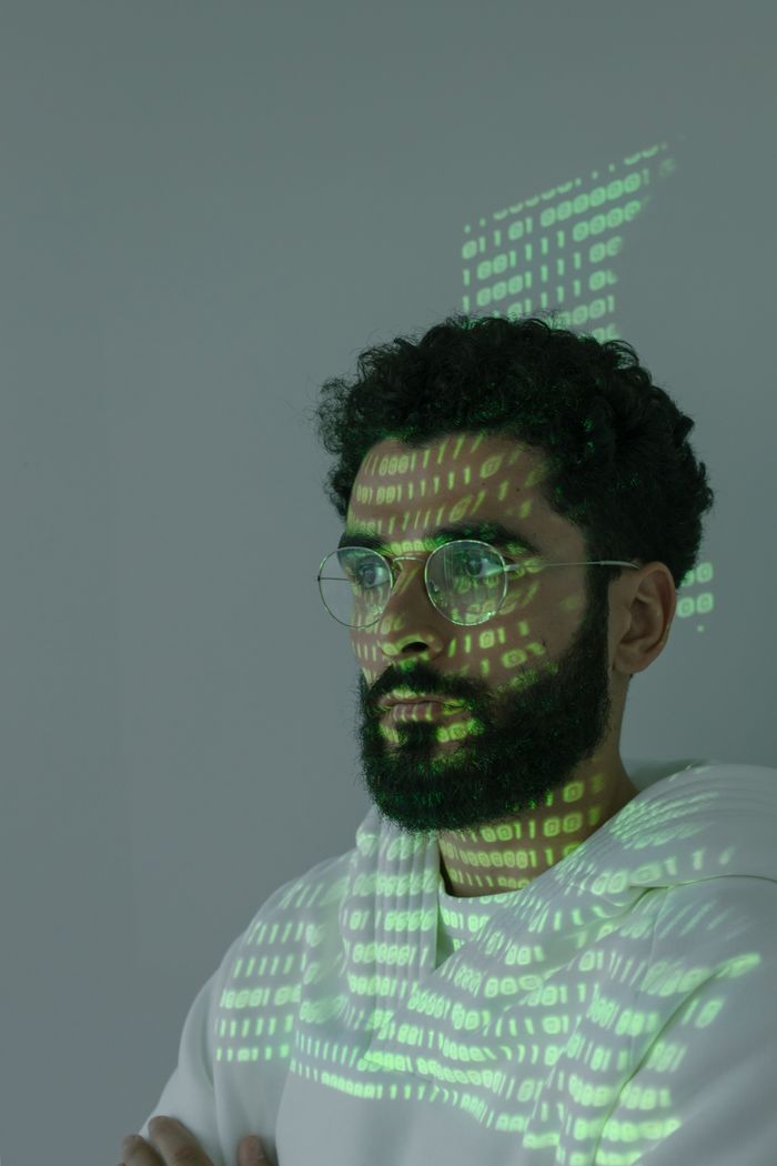 Close-up of a man with digital code projected on his face symbolizing cyber security and technology